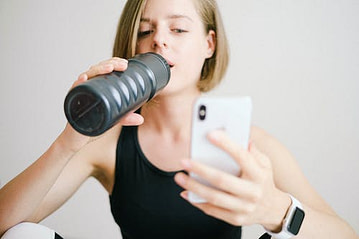 woman drinking water with cell phone